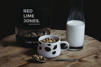 Bowl of granola, a cup and a glass of milk on a wooden table